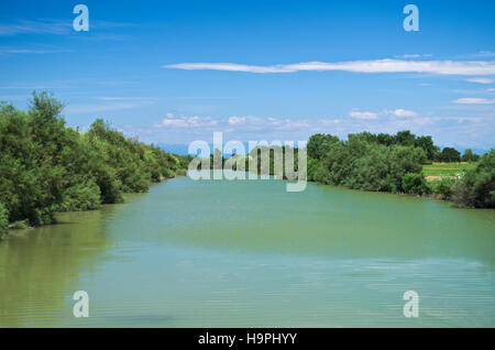 Estate vista del fiume Lemene nella pianura veneta con le Alpi in background Foto Stock
