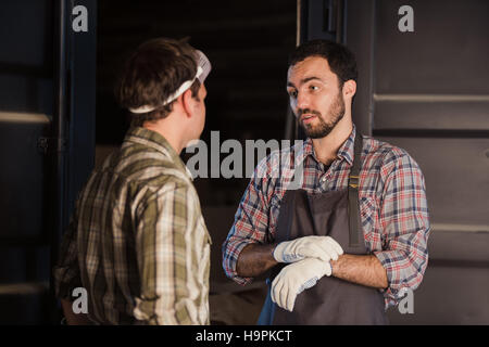 Giovane falegname ottiene denaro per il suo lavoro in falegnameria officina Foto Stock