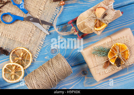 Accessori, decorazione, slitta di legno e avvolti di regali di Natale o di altra celebrazione giacente su schede Foto Stock