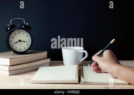 Man mano con penna che scrive su notepad, su sfondo bianco. Foto Stock