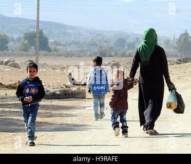 Damasco, Siria. 24 Novembre, 2016. Gli sfollati a piedi su una strada polverosa in Mualaqa nella periferia di Damasco, Siria, nov. 24, 2016. La città di 400 famiglie hanno ospitato un ulteriore 800 famiglie che sono fuggiti a causa della guerra da aree vicine. © Ammar Safarjalani/Xinhua/Alamy Live News Foto Stock