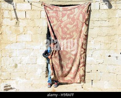 Damasco, Siria. 24 Novembre, 2016. Un ragazzo spostato sta dietro all'ingresso della sua abitazione in Mualaqa nella periferia di Damasco, Siria, nov. 24, 2016. La città di 400 famiglie hanno ospitato un ulteriore 800 famiglie che sono fuggiti a causa della guerra da aree vicine. © Ammar Safarjalani/Xinhua/Alamy Live News Foto Stock