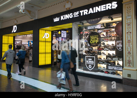 Persone che passano il King of Trainers JD Sports all'INTU Trafford Centre Manchester. Regno Unito novembre 2016. Offerte di vendita per il Black Friday nel weekend. Periodo di shopping natalizio in centro città, negozi, negozi, moderno, stile, occasioni, marchi commerciali, moda, pubblicità, persona, consumatori, acquirenti di Natale, persone che fanno acquisti scontati e spese consumer nel weekend del Black Friday considerato il più grande evento di shopping dell'anno. I rivenditori del Regno Unito hanno abbracciato le offerte post-festività statunitensi, anche se molti clienti sono rimasti sorpresi dagli sconti a tutta parete nei loro negozi preferiti Foto Stock