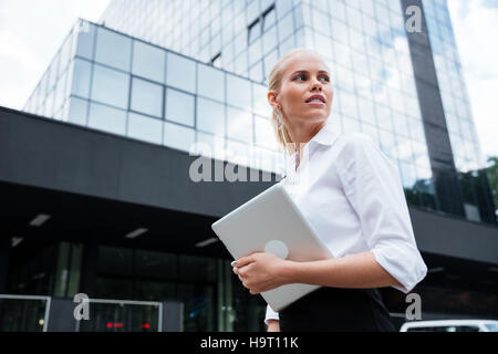 Business donna lavora con la compressa all'aperto in piedi vicino all'ufficio Foto Stock