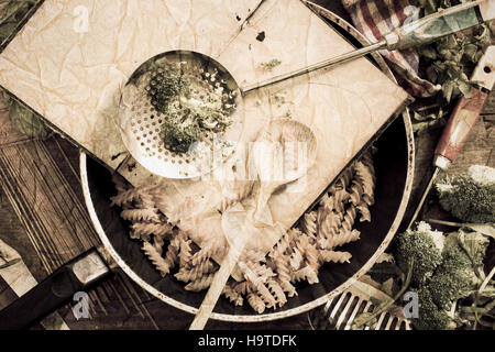 Libro di cucina con cucchiaio, tagliatelle e broccoli in padella - vintage testurizzato immagine retrò, disposti su un vecchio tavolo in legno Foto Stock