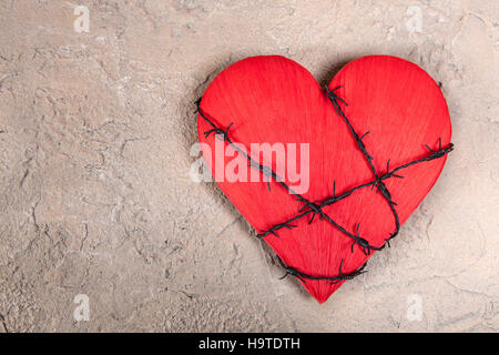Barebed filo avvolto intorno ad un cuore rosso su sfondo grungy Foto Stock