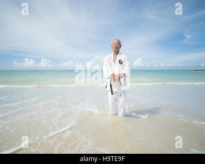 Anziani la cintura nera karate master formazione sulla spiaggia in Okinawa. Okinawa è uno dei la più lunga aspettativa di vita nel mondo Foto Stock