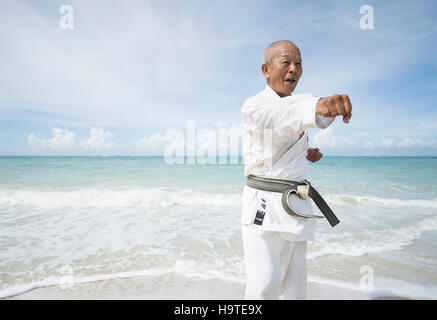 Anziani la cintura nera karate master formazione sulla spiaggia in Okinawa. Okinawa è uno dei la più lunga aspettativa di vita nel mondo Foto Stock