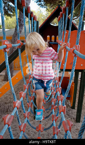 Due anni di arrampicata ragazza ponte di corde, parco giochi, isola di Formentera, isole Baleari, Spagna Foto Stock