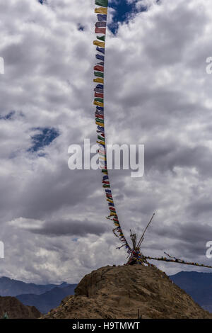 Fila di bandiere di preghiera in esecuzione dal Namgyal Tsemo Tempio a una collina adiacente. Foto Stock