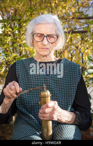 Senior donna la macinazione del caffè su un vintage macinino da caffè Foto Stock