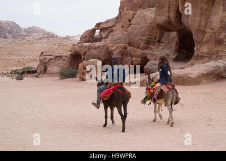 Beduin uomini a cavallo degli asini nelle antiche Nabatean città di Petra, Giordania Foto Stock