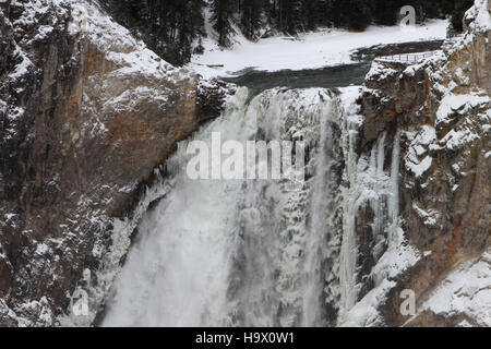 Una foto invernale scattata sull'orlo delle Lower Falls nel parco nazionale di Yellowstone. Il paesaggio ghiacciato mostra la bellezza unica delle cascate durante i mesi più freddi, sottolineando i diversi cambiamenti stagionali del parco. Foto Stock