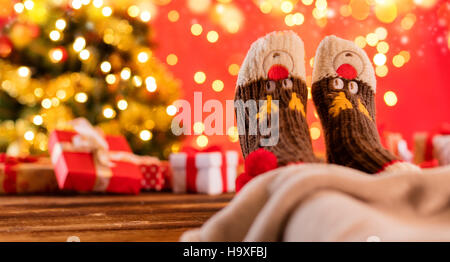 Dettaglio della donna in piedi in calze di lana, blur albero di Natale sullo sfondo Foto Stock