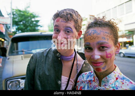 Giovane donna e ragazzo lungo la 'Ave' anni '80 sorridendo con volti dipinti con parole University District Seattle Washington state USA Foto Stock