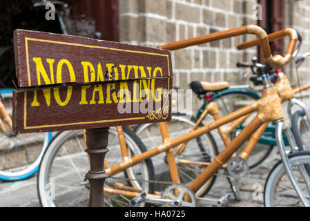 Nessun parcheggio. Incrinato 'no parcheggio' segno davanti di bambù e acciaio biciclette su una strada a Manila nelle Filippine Foto Stock