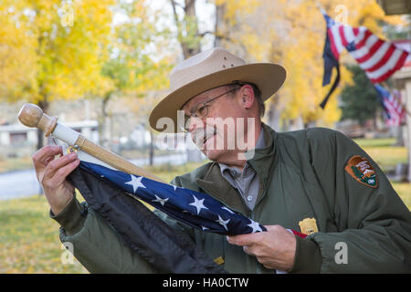 I ranger del parco nazionale di Yellowstone onorano la giornata nazionale dei vigili del fuoco attaccando nastri neri alle bandiere lungo la fila degli ufficiali, riconoscendo i sacrifici e il coraggio dei vigili del fuoco a livello nazionale. Foto Stock