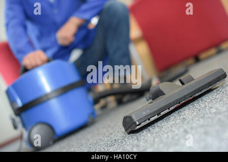 Primo piano dell'uomo accovacciato da aspirapolvere Foto Stock