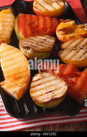 Grigliata di mela, melone, pera, anguria e pesca su una padella per grigliare closeup. In verticale Foto Stock