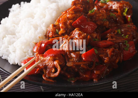 Riso con stufati di carne di maiale in salsa agrodolce sulla piastra closeup. Posizione orizzontale Foto Stock