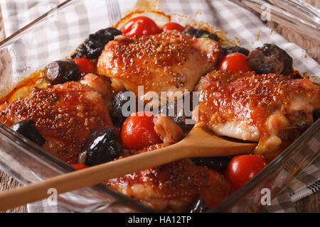 Coscia di pollo al forno con pomodori e funghi porcini vicino fino in una teglia sul tavolo. Posizione orizzontale Foto Stock