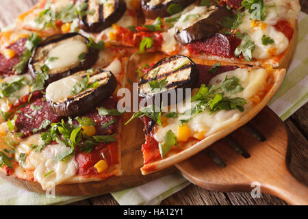 Pizza con le melanzane, salame e mozzarella close up su una tavola di legno orizzontale. Foto Stock