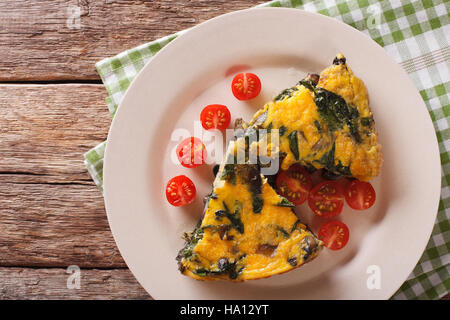 Fette di frittata con spinaci, formaggio cheddar e funghi su una piastra su un tavolo di close-up. Vista orizzontale dal di sopra Foto Stock