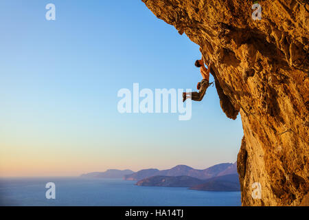 Rocciatore saltando sulle maniglie mentre alpinismo rupe a strapiombo Foto Stock