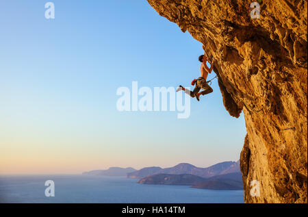 Rocciatore saltando sulle maniglie mentre alpinismo rupe a strapiombo Foto Stock