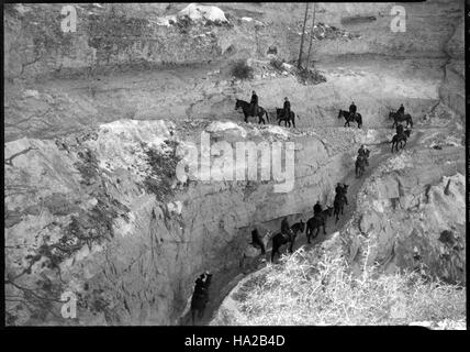 Questa fotografia storica cattura i muli che navigano lungo il South Kaibab Trail nel Parco Nazionale del Grand Canyon. Il sentiero, sviluppato all'inizio del XX secolo, rimane un percorso chiave per i visitatori e gli animali da imballaggio che attraversano il terreno accidentato del canyon. Foto Stock
