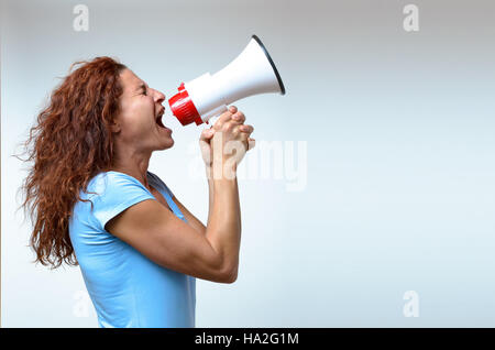 Giovane donna gridando in un megafono, vista laterale su bianco concettuale del un rally o protesta Foto Stock