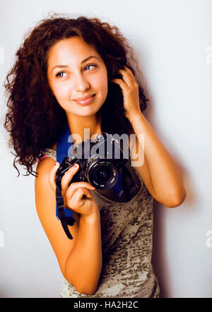 Poco carino tanga teenage ragazza con i capelli ricci tenere la fotocamera, fotografo in un colpo, lo stile di vita di persone concetto Foto Stock