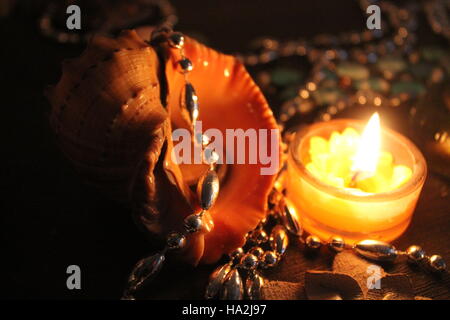 Bel big shell dal mare decorato argento perle e masterizzare candela bella composizione per la celebrazione Foto Stock