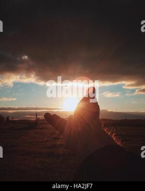 Silhouette di una mano di un uomo di raggiungere per sun Foto Stock