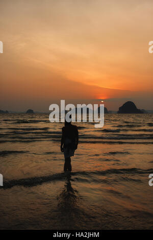 Silhouette di una donna in piedi sulla spiaggia al tramonto, Khoa Lak, Thailandia Foto Stock