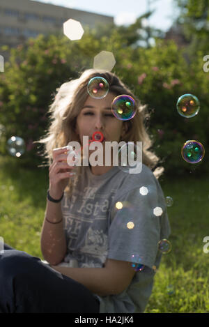 Giovane donna soffiando bolle di sapone Foto Stock