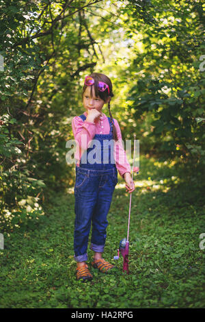 Ragazza in piedi nella foresta con canna da pesca Foto Stock