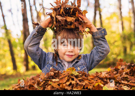 Ragazzo giocando in un mucchio di foglie di autunno Foto Stock