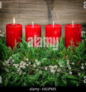 Avvento corona di decorazione con rosso quattro candele accese. In stile vintage tonica foto Foto Stock