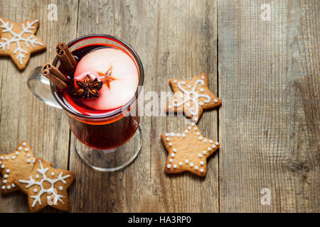 Natale bevanda calda - vin brulé con frutti, il bastoncino di cannella, anice stellato e festa di Natale gingerbread i cookie in legno rustico sfondo con Foto Stock