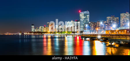 Jersey City panorama sullo skyline di notte, che si riflette nel fiume Hudson, con Verrazano-Narrows Bridge in background Foto Stock