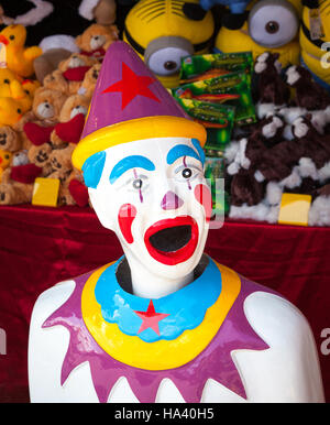 Un coloratissimo clown arcade con premi impilati dietro di lui. Foto Stock