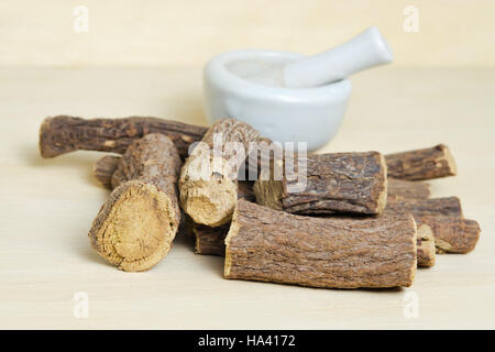 Cumulo di terra bastoncini di liquirizia isolati su legno (chiamato anche come Glycyrrhiza acanthocarpa, Glycyrrhiza glabra, glabra liquirizia, liquirizia, o di tabacco Foto Stock