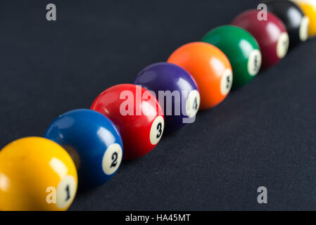 Palle da biliardo in una fila sul tavolo blu. Foto Stock