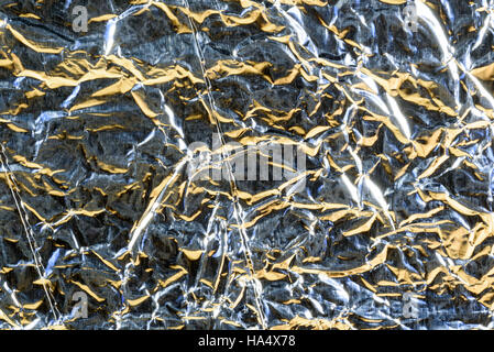 Crumpled alluminio foglio di stagno texture con riflessi di luce sull'argento metallizzato brillante avvolgimento Foto Stock
