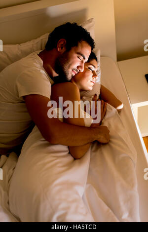 Abbracciando coppia giovane dormire nel letto Foto Stock