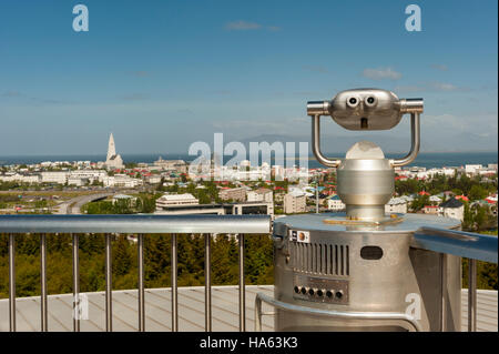 Una gettoniera viewer puntato al centro di Reykjavik, Islanda, dall'Perlan un deck di visualizzazione, con Hallgrimskirkja nel telaio. Foto Stock