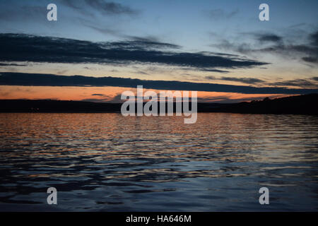 Un estate tramonto sul mare in dale, pembrokeshire. lo sbiadimento di luce dorata si confonde con le nuvole di notte. Foto Stock