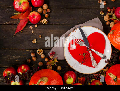Composizione di autunno di zucche, mele e la piastra con la forchetta e coltello su un rustico sfondo di legno. La Giornata del ringraziamento concept Foto Stock