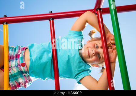 Bambina giocando sulla Monkey bar in un giardino estivo Foto Stock